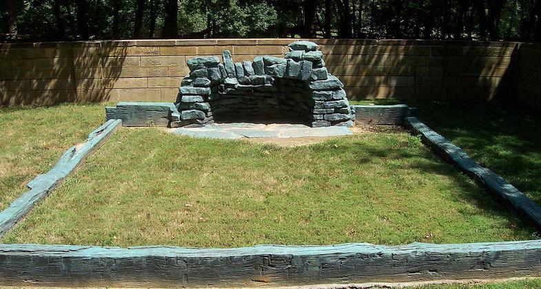 A bronze casting of sill logs and fireplace hearthstones symbolizes a cabin that the Lincolns began building in 1829. Photo by Cool10191/wiki.