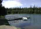 A metal and wooden dock and a small white boat floating beside in shallow water. Photo by USFS.