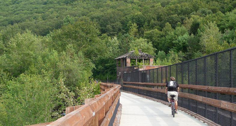 The bridge carrying the Lehigh Gorge Trail and a railroad over the Lehigh River in Jim Thorpe, PA. Photo by Listroiderbob2.